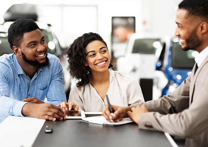 Happy couple purchasing a new car at a dealership