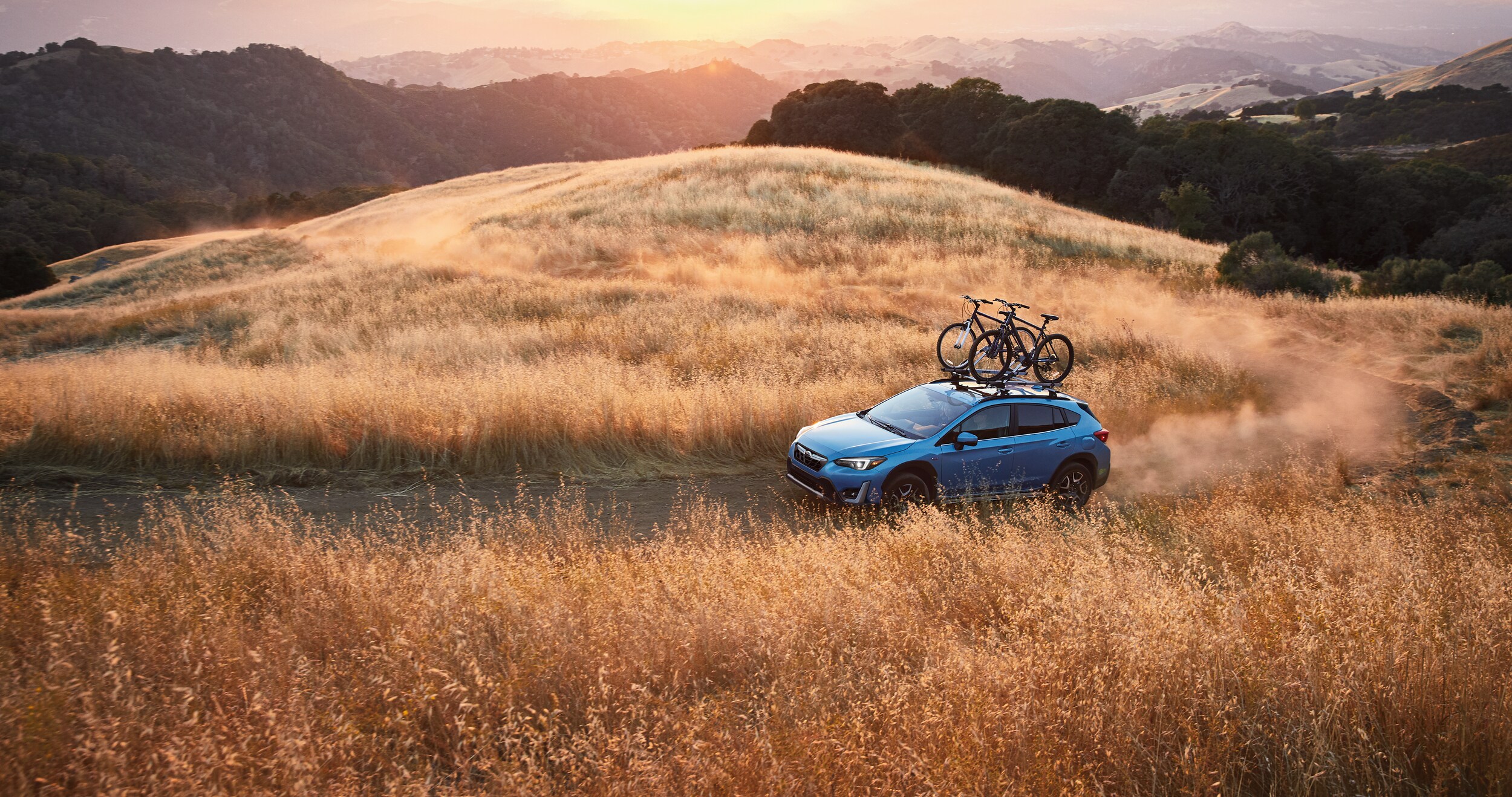 A 2023 Crosstrek Hybrid driving on a dirt road.