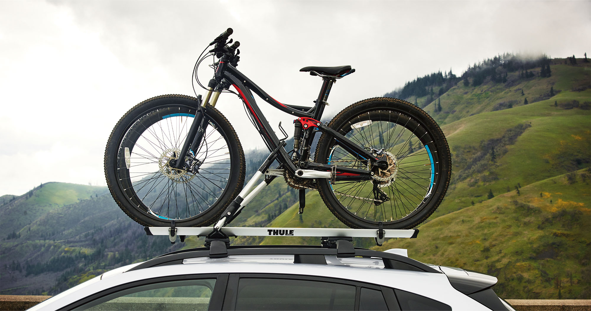  A close-up of mountain bikes in a bike carrier mounted on the raised roof rails of the 2023 Crosstrek.