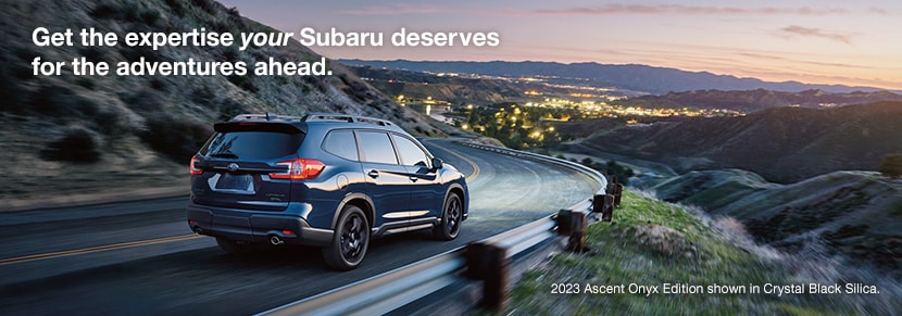 2023 Subaru Ascent Onyx Edition shown in Crystal Black Silica driving on a road on the side of a mountain.