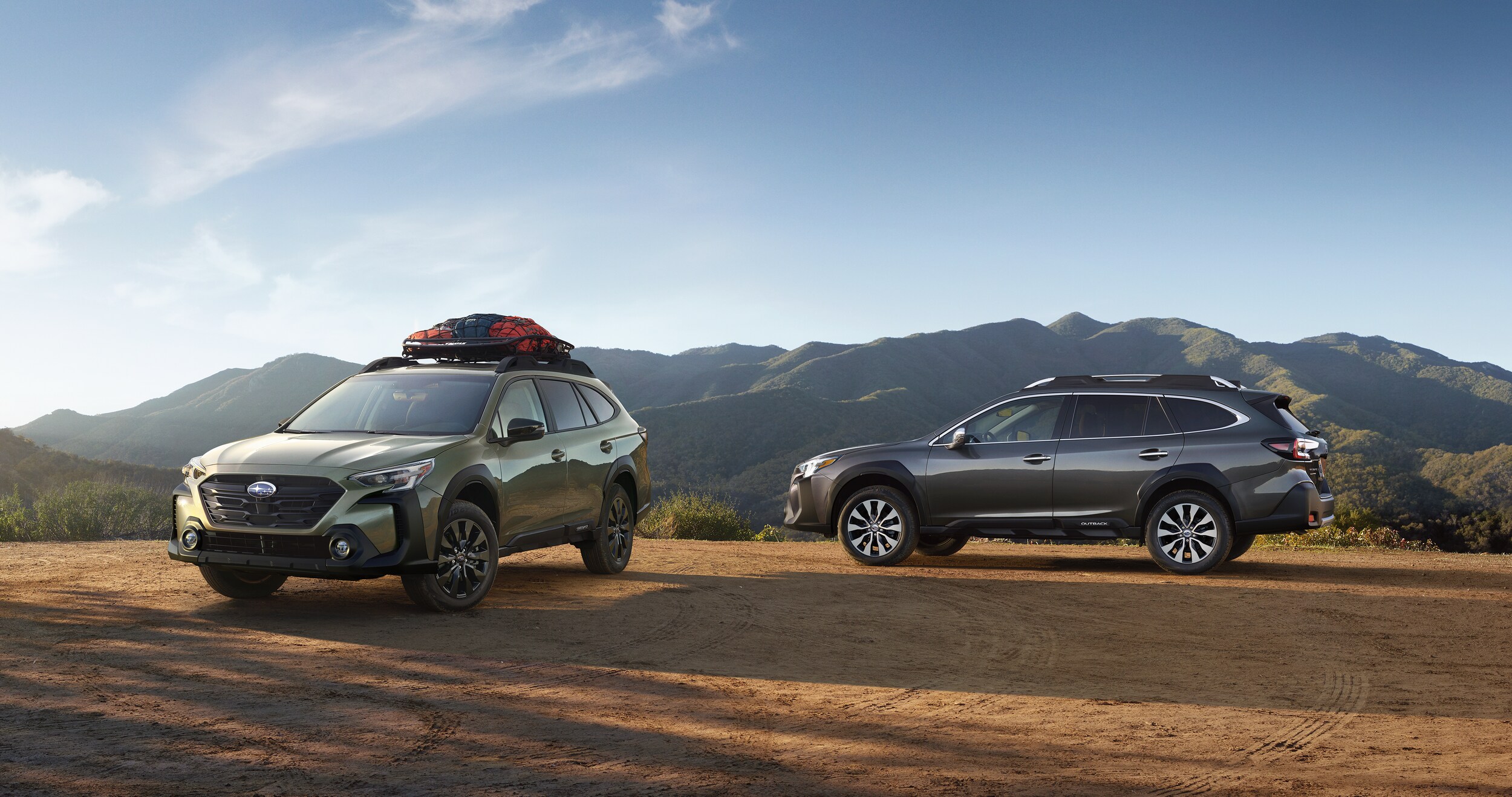A pair of 2023 Outback vehicles parked in the mountains