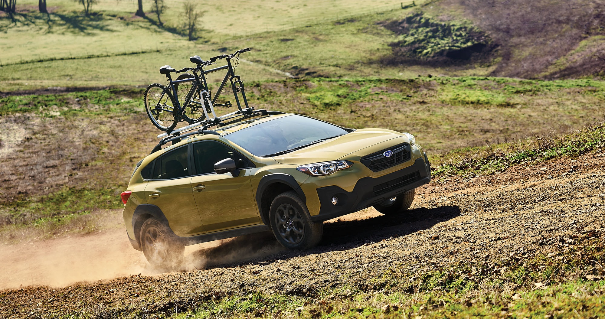 A 2023 Crosstrek climbing a hilly dirt road.