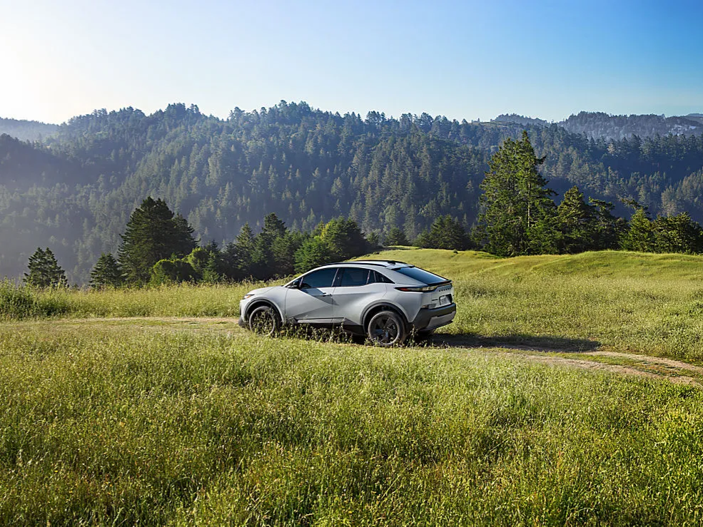 A Subaru Uncharted SUV is parked on a grassy hill in the mountains.