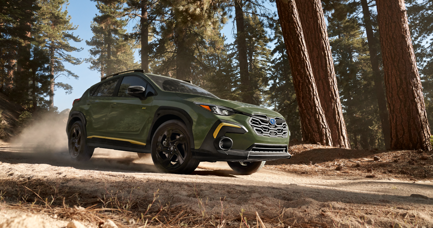 A 2025 Crosstrek Sport driving on a mountain road and through a forest.