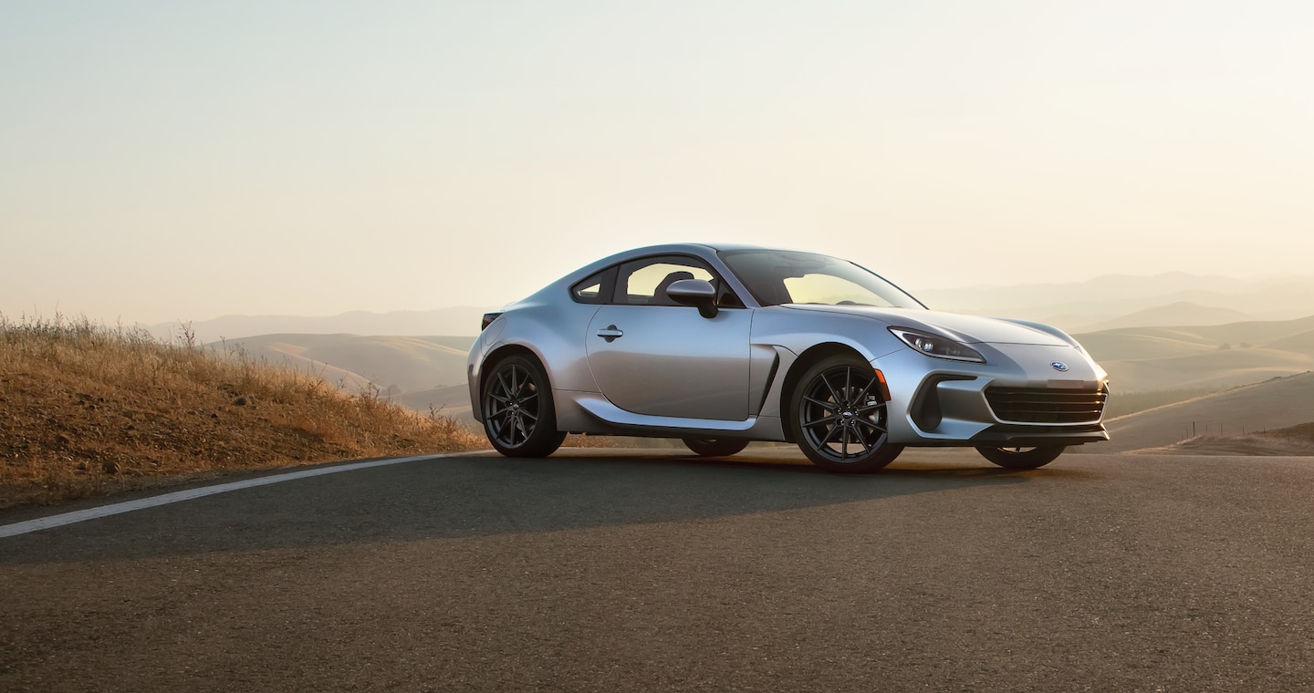 A silver BRZ parked on a road overlooking a hilly landscape.