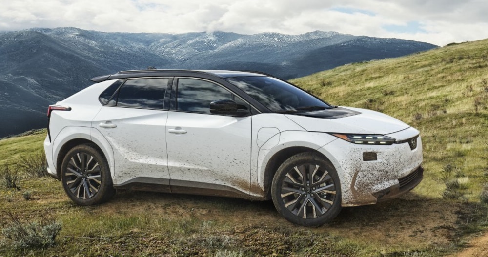 A static image of a white 2027 Subaru Solterra parked on a grassy hill.