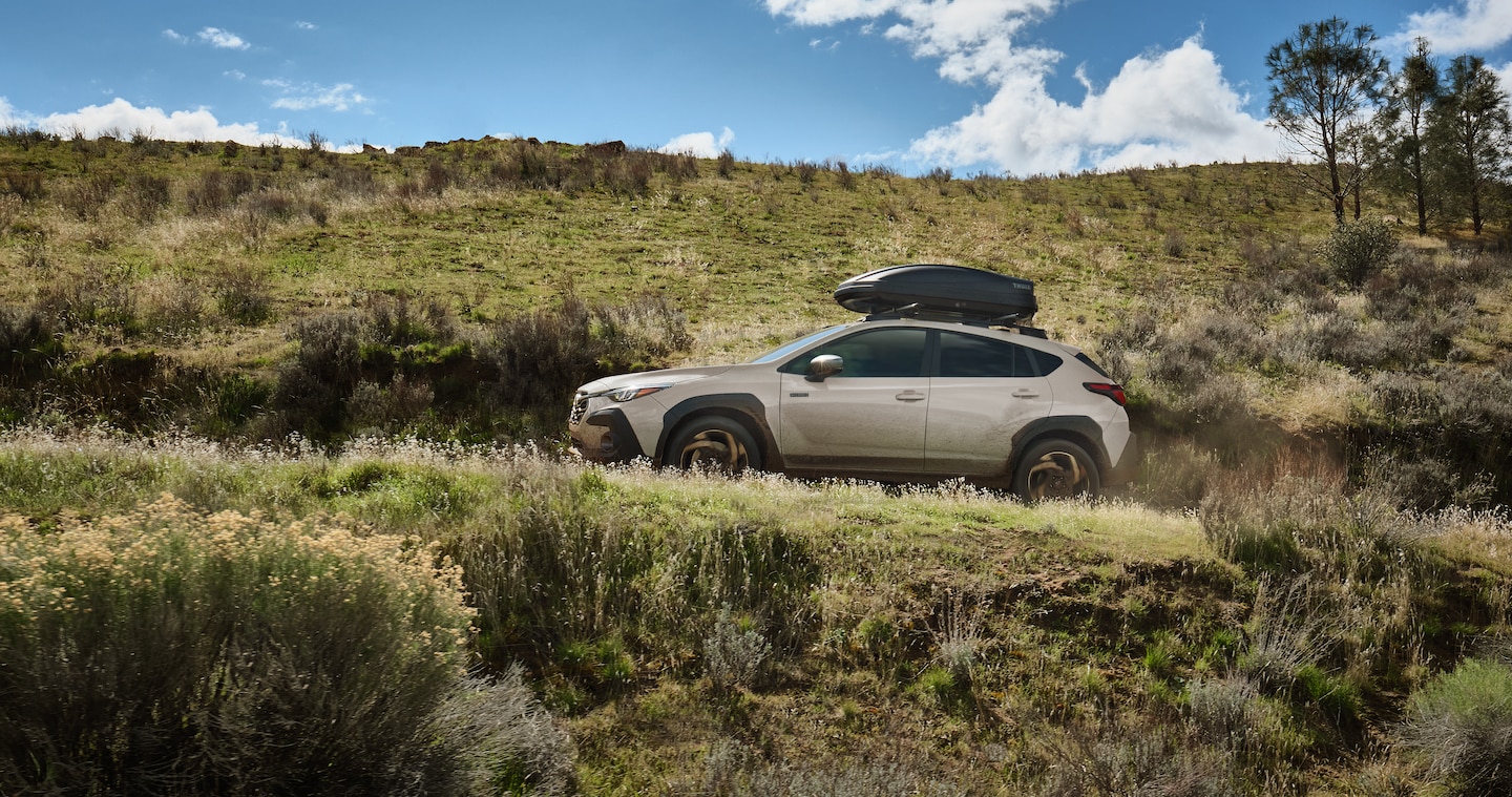 2026 Crosstrek Hybrid parked in a hilly, tree-covered landscape.