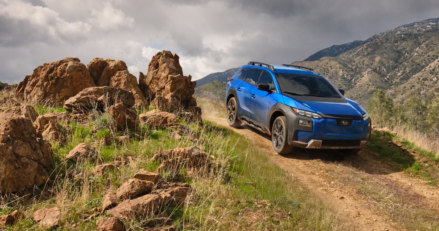  A 2026 Subaru Trailseeker in blue drives down an arid hill.
