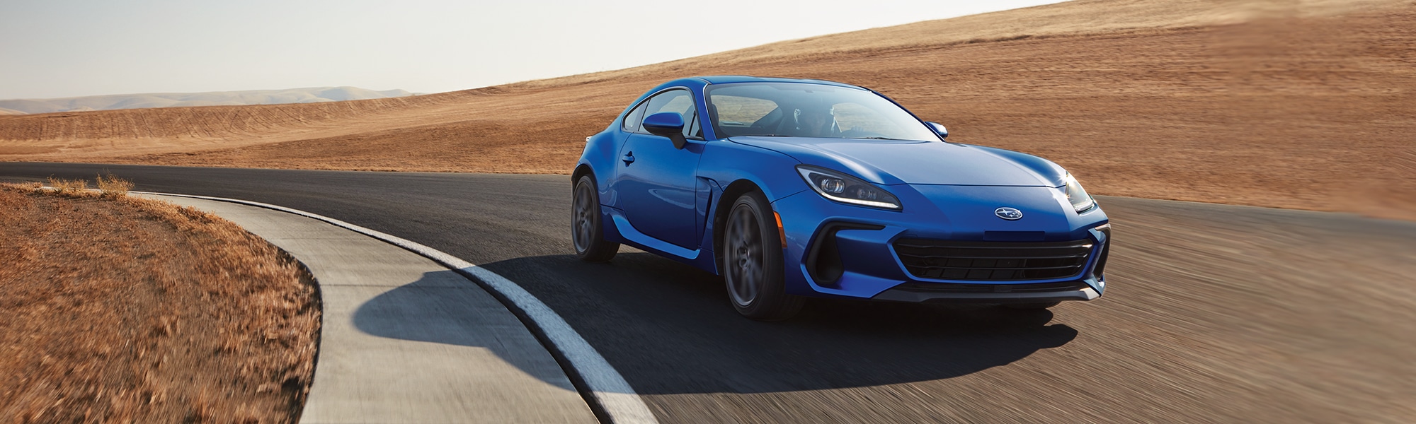  A 2023 blue BRZ driving on a racetrack.
