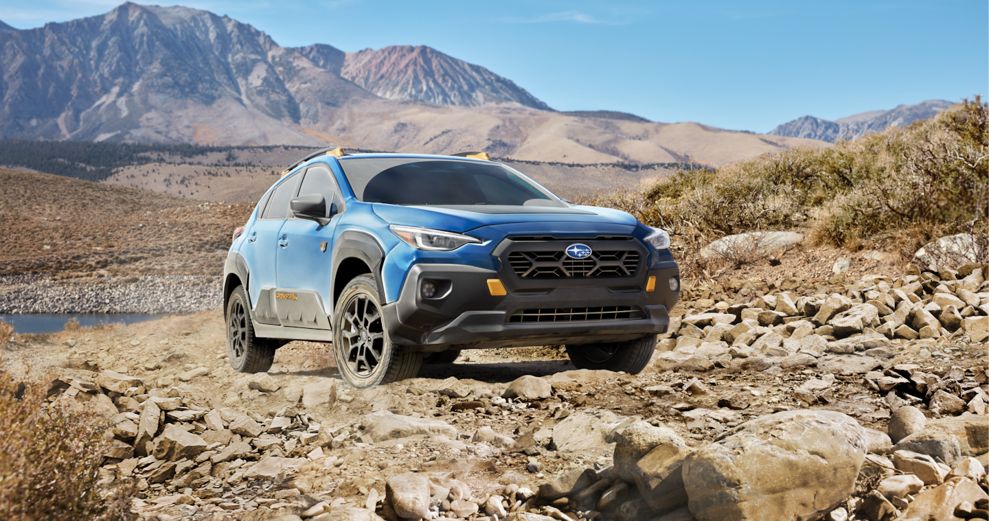 A blue 2024 Subaru Crosstrek Wilderness climbs over rock terrain