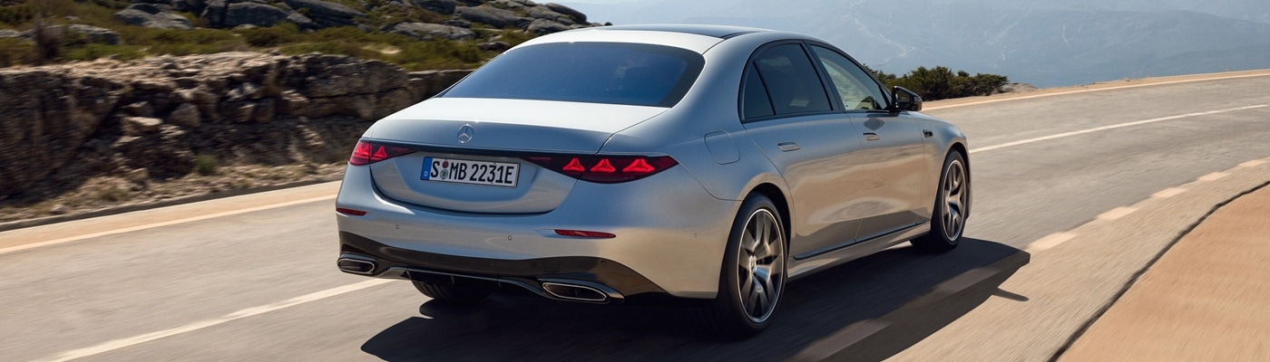 Silver Mercedes-Benz S-Class driving away on a sunny road