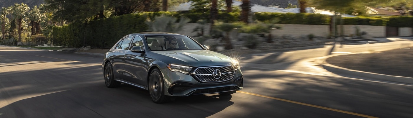 Grey Mercedes-Benz E-Class Sedan driving on a suburban street