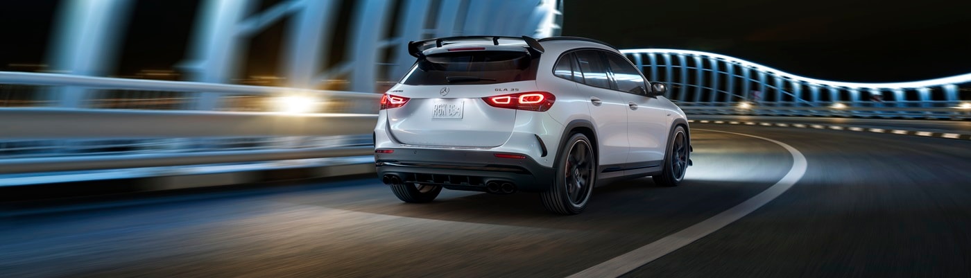 White Mercedes-Benz AMG GLA 35 driving in a city at night