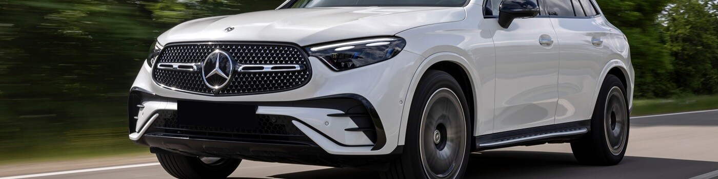 Grille of a White Mercedes-Benz AMG GLC driving on a road in the forest
