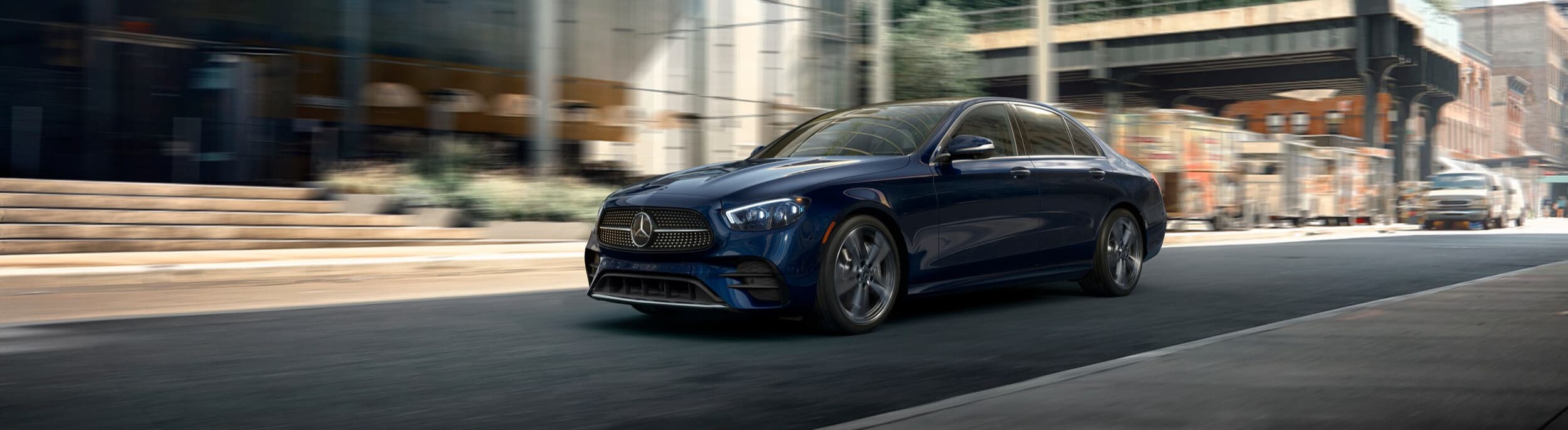 Blue Mercedes-Benz E-Class Sedan driving on a city street