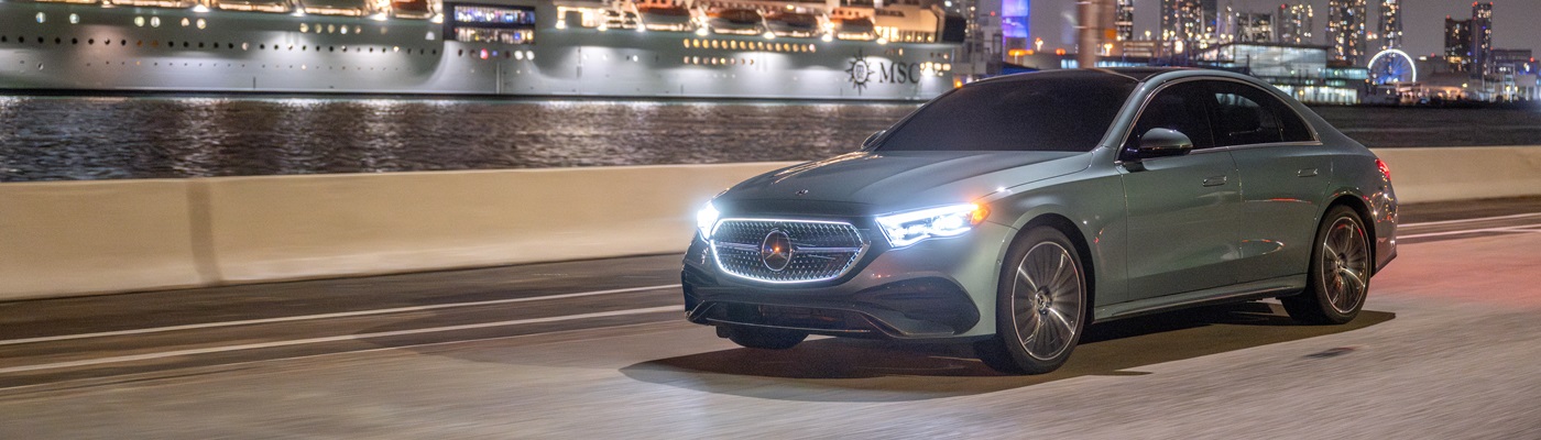 Green Mercedes-Benz E-Class Sedan driving at a port at night