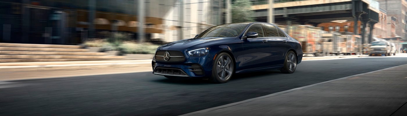 Blue Mercedes-Benz E-Class Sedan driving on a city street