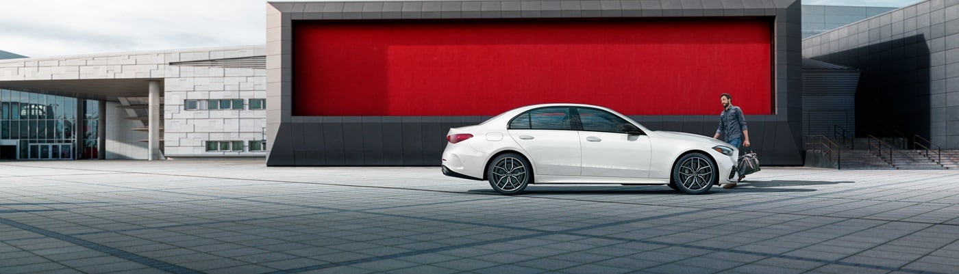 White Mercedes-Benz C-Class parked in front of a modern building