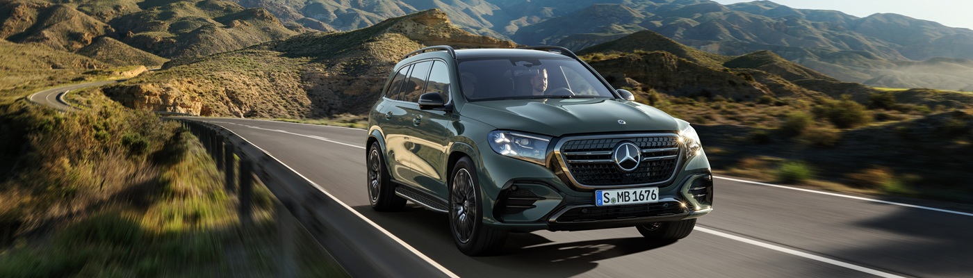 Green Mercedes-Benz GLS SUV driving on a hilly highway