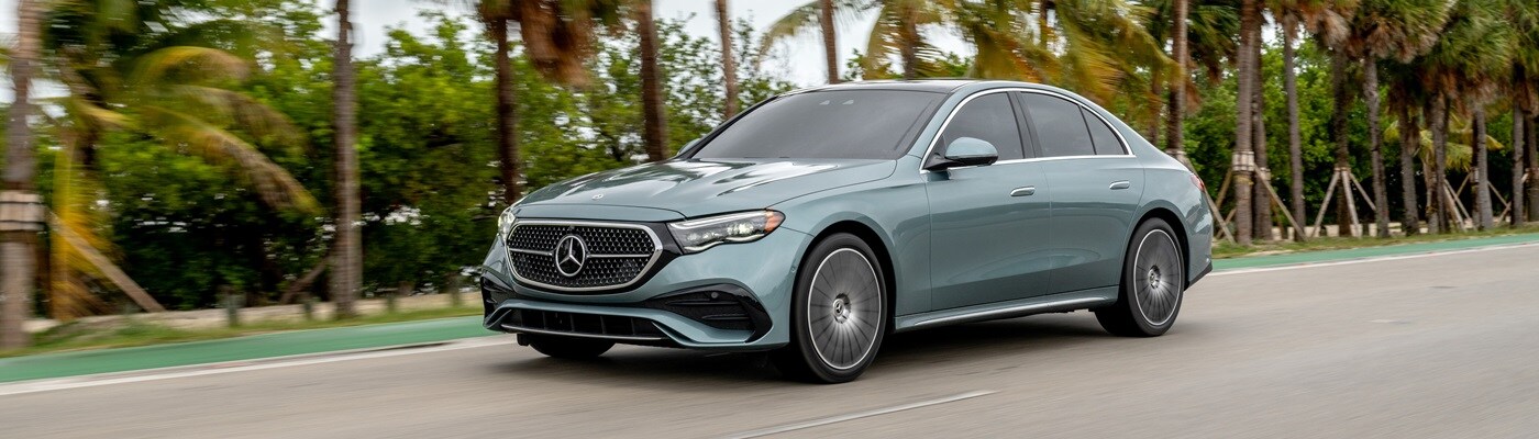 Mercedes-Benz E-Class driving on a street by palm trees