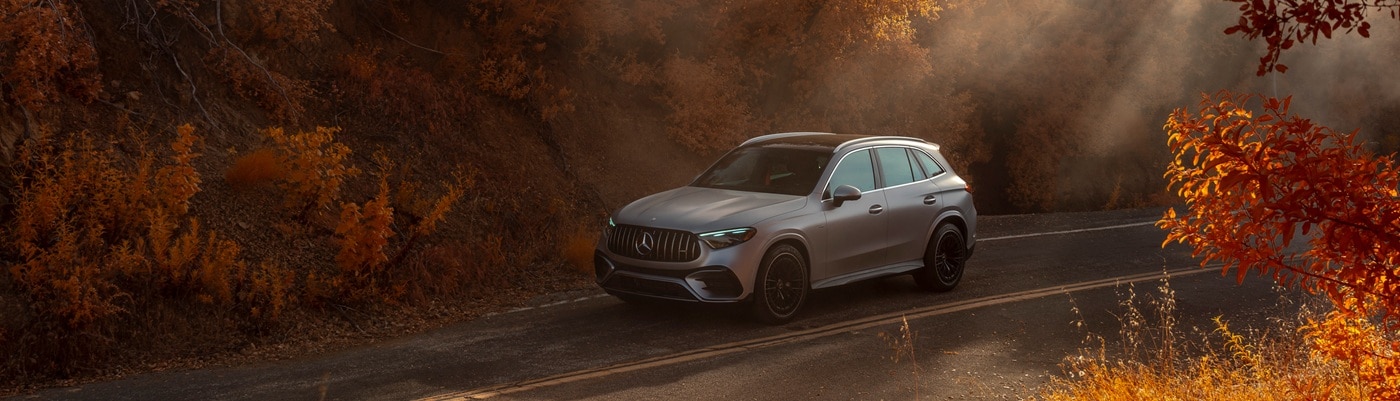 Silver Mercedes-Benz AMG GLC driving on a road in autumn