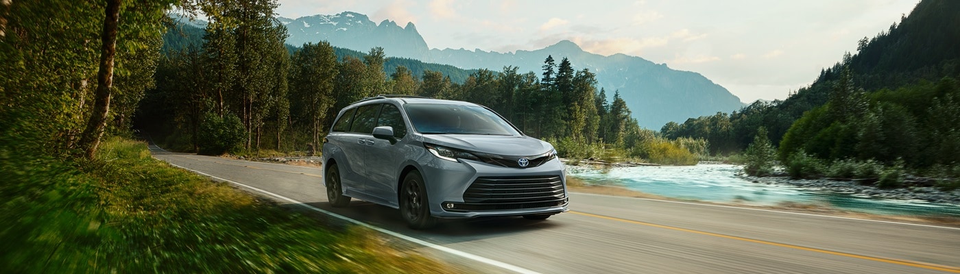 Grey Toyota Sienna Woodland driving on a road in the forest
