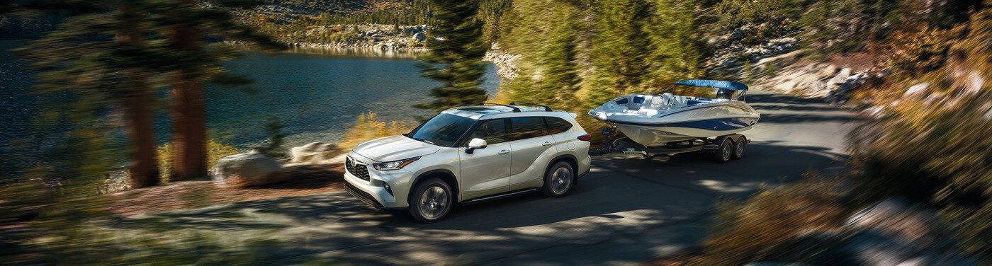 White Toyota Highlander Platinum towing a boat on a mountain road