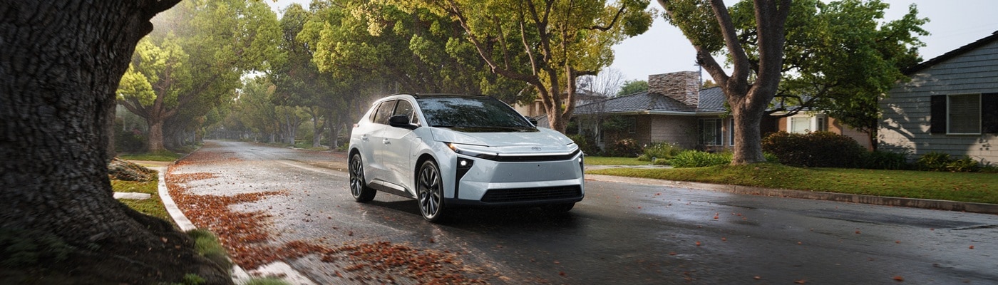 White Toyota bZ SUVs Limited driving on a street in the suburbs