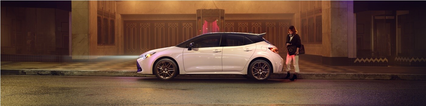 White Toyota Corolla Hatchback Nightshade parked in front of a theater at night