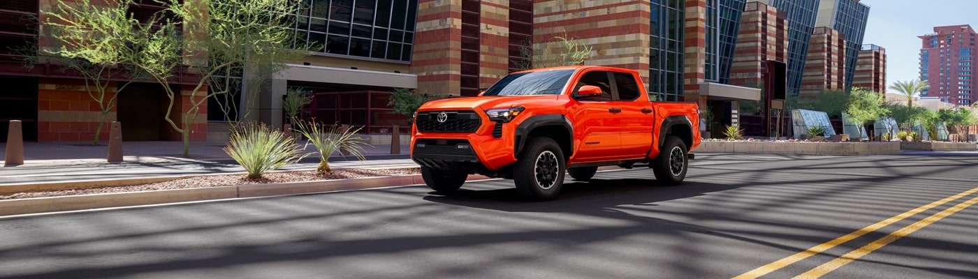 Orange Toyota Tacoma TRD Off Road driving on a street in a city