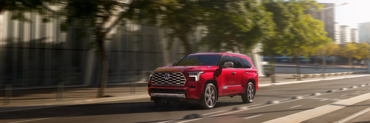 red Toyota Sequoia driving on a road in a city