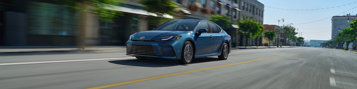 Blue Toyota Camry XLE driving on a road in a city