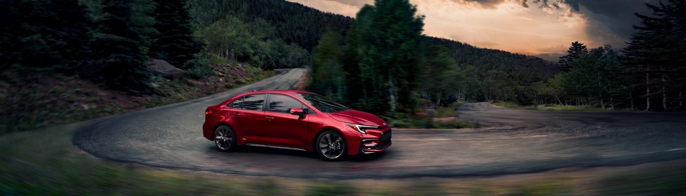 Red Toyota Corolla Hybrid SE driving in the forest
