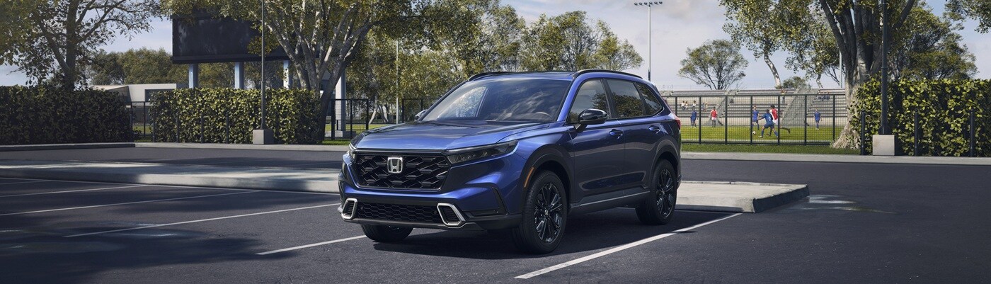Blue CR-V Hybrid Sport Touring parked in front of a rec field