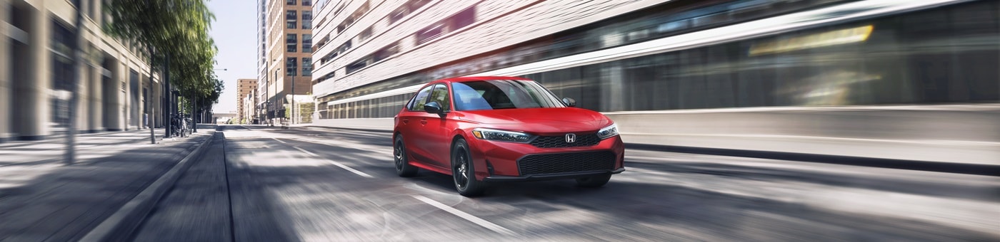 Red Honda Civic Sport Touring Hybrid driving in a city