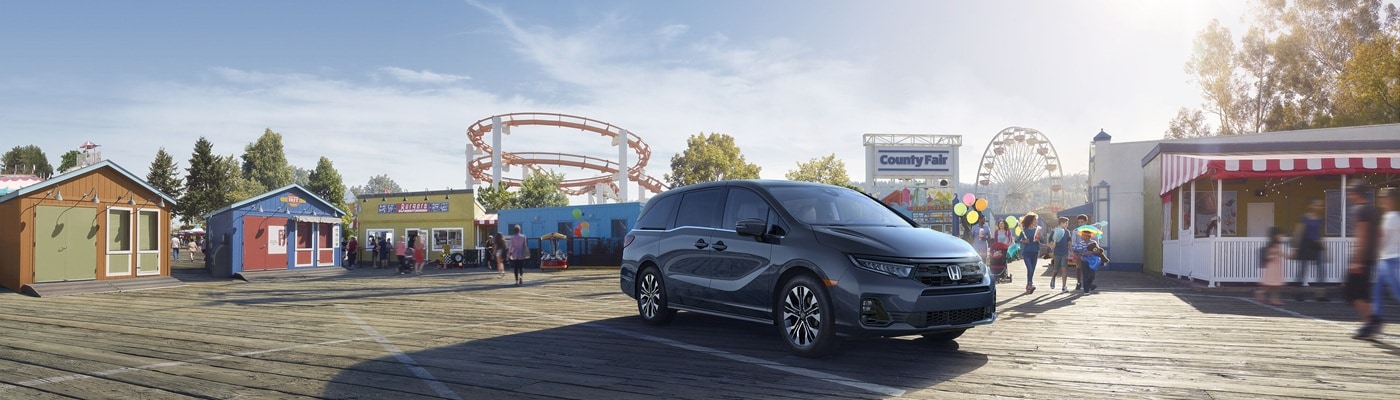 Grey Honda Odyssey Elite minivan parked at a county fair
