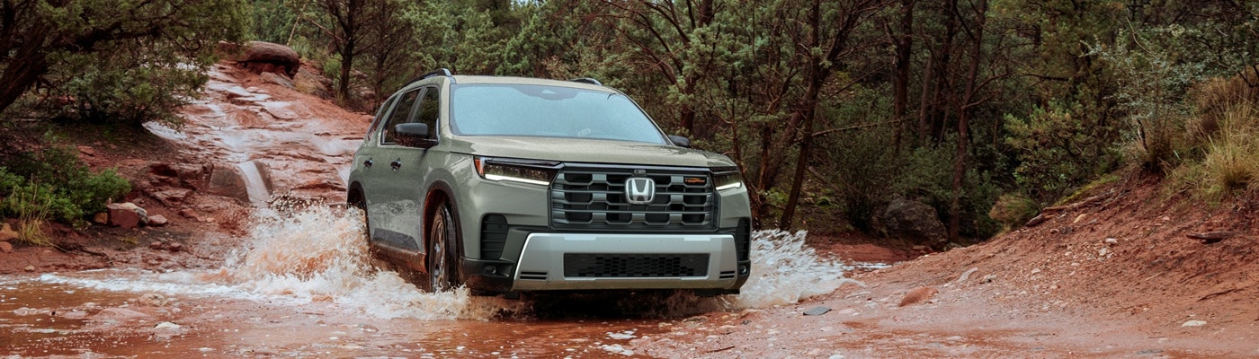 Green Honda Pilot TrailSport fording a clay river