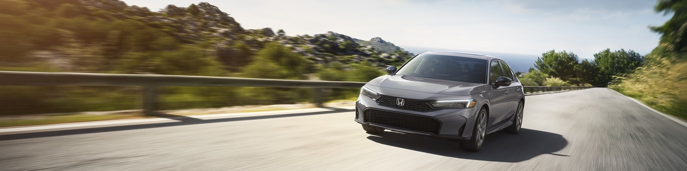Grey Honda Civic Hybrid driving on a road near the coast