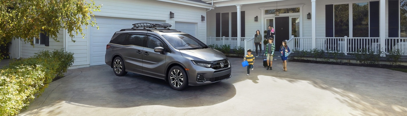 Grey Honda Odyssey Elite Minivan parked in the driveway of a suburban house