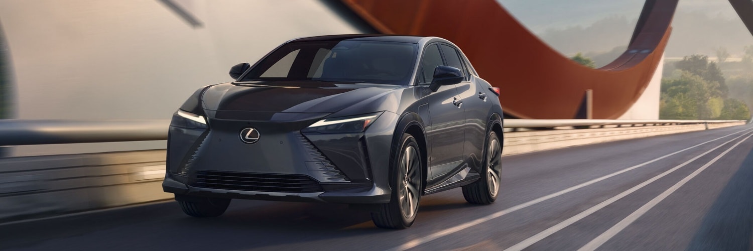 Black 2025 Lexus RZ 300e driving across a bridge