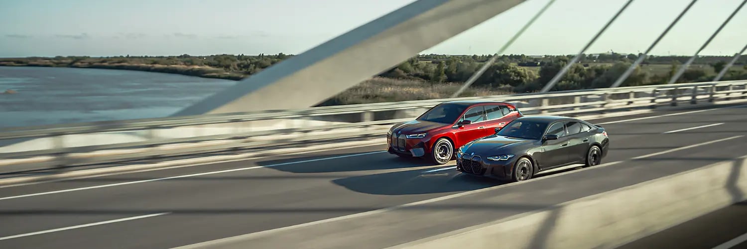 BMW iX and i4 BMW iX and i4 driving across a bridge