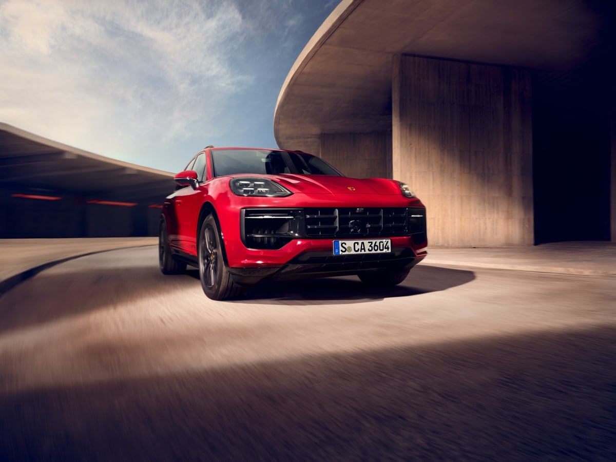 Red Porsche Cayenne GTS driving around a modern concrete structure