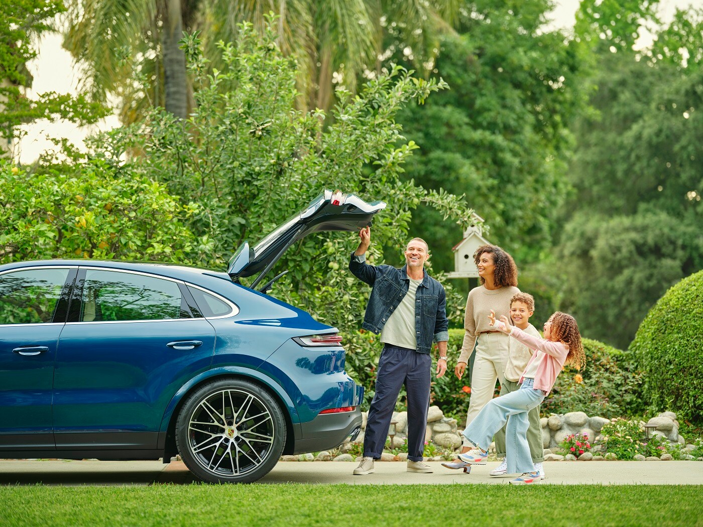 Porsche Cayenne Coupe Porsche Cayenne Coupe with its trunk open and a family standing beside it