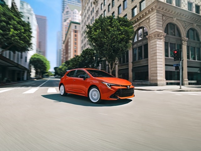 Orange Toyota Corolla Hatchback FX driving on a city street