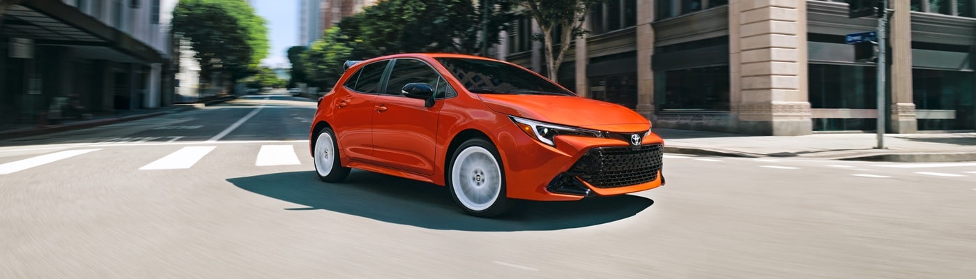 Orange Toyota Corolla Hatchback FX driving on a city street