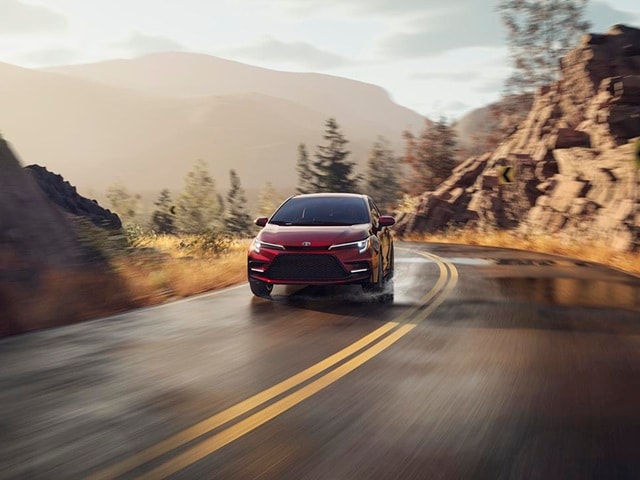 Red Toyota Corolla Hybrid driving on a moutain road