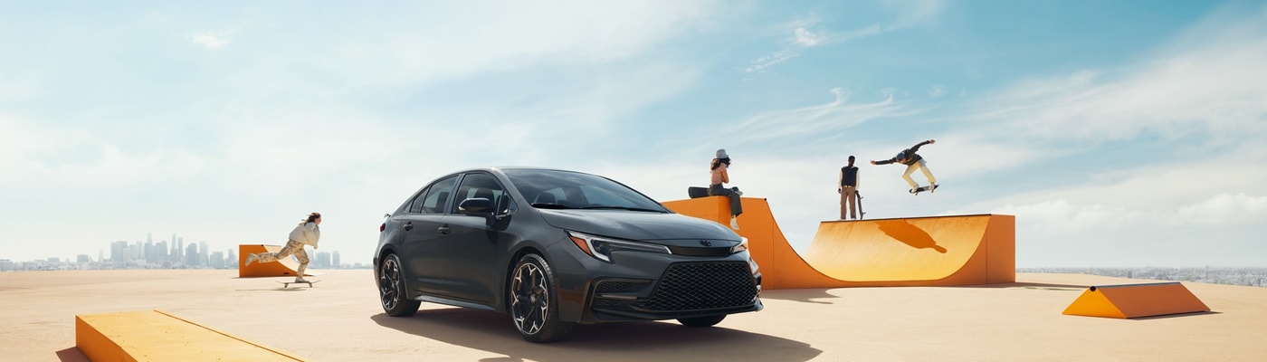 Grey Toyota Corolla FX parked in front of a skatepark