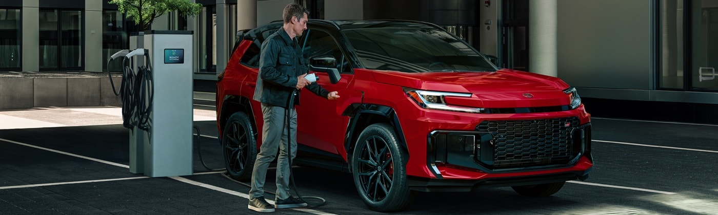 Red Toyota RAV4 PHEV being plugged into in a city