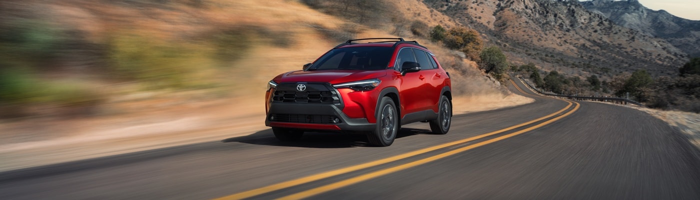 Red Toyota Corolla Cross XLE driving on a road in the desert