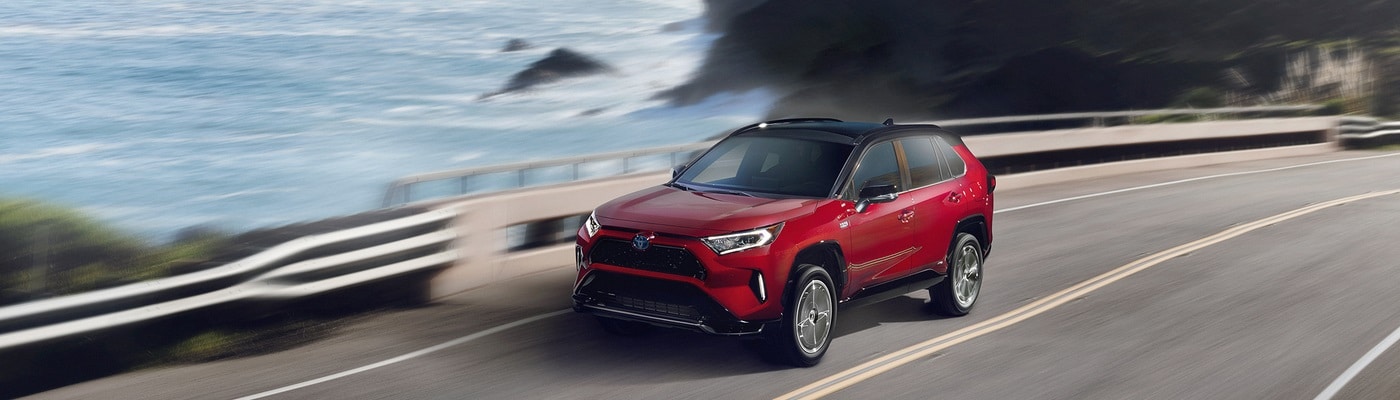 Blue Toyota RAV4 PHEV driving on the coast